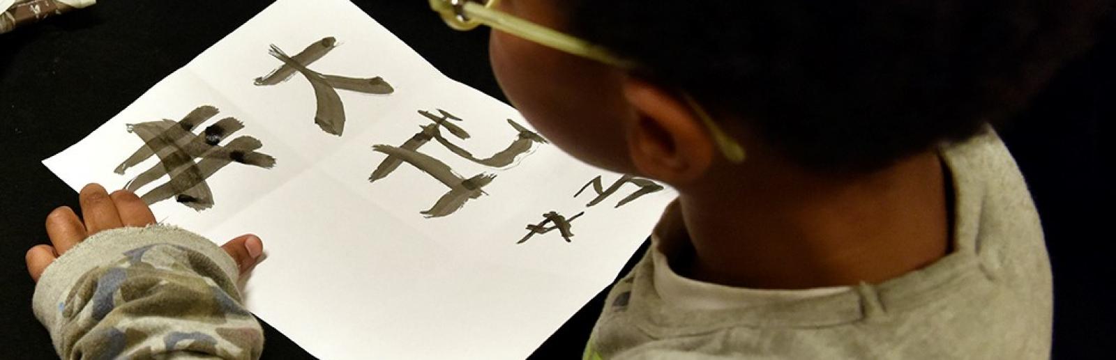 Atelier jeune public, enfant entrain d'écrire à l'encre chinoise Atelier jeune public, enfant entrain d'écrire à l'encre chinoise